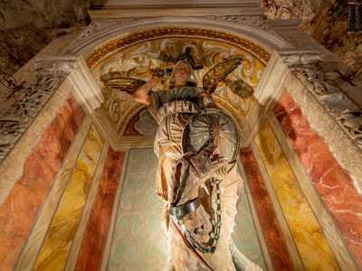 La scultura, ricavata da un unico blocco di pietra policroma locale, raffigura il santo in abiti da guerriero con scudo e spada sguainata mentre tiene alla catena un drago, simbolo del diavolo